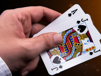 Featured Image: Blackjack’s Name Origins - A man holding a card hand with an ace and a black jack of spades