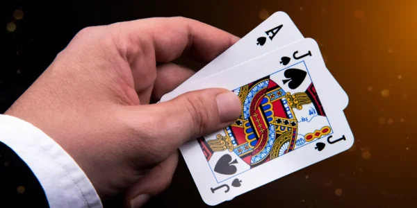 Featured Image: Blackjack’s Name Origins - A man holding a card hand with an ace and a black jack of spades